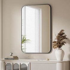 a white cabinet with a mirror on top of it next to a vase filled with flowers