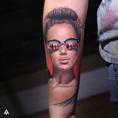 a woman's arm with a tattoo on it that has an image of a woman wearing sunglasses