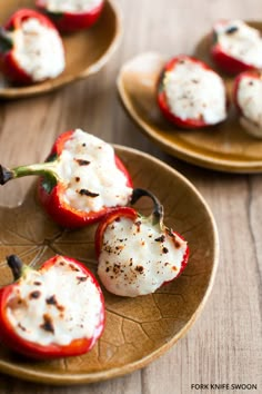 three red peppers with cheese on them sitting on a brown and yellow plate next to another one