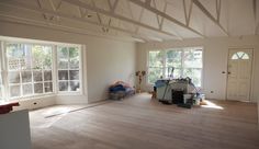 an empty living room with wood floors and white paint on the walls, windows, and doors