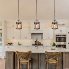 two wooden chairs sit at an island in the middle of a kitchen with stainless steel appliances