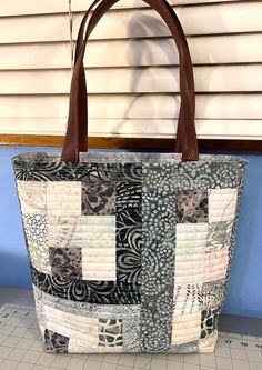 a handbag sitting on top of a cutting board next to a window with blinds