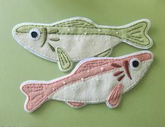 two embroidered fish sitting on top of a green surface