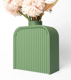 a green vase with pink flowers in it