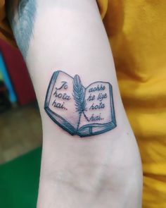 a person with a tattoo on their arm that has an open book and a feather