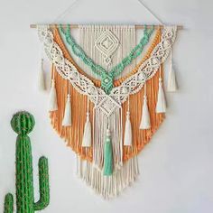 the wall hanging is decorated with tassels and fringes, along with a cactus