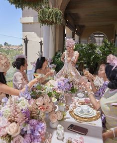 a group of women sitting around a table with plates and cups in front of them