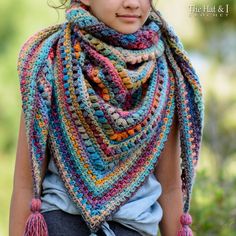 a woman wearing a multicolored crocheted shawl with tassels