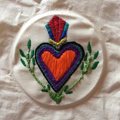 an embroidered heart on a white plate with green leaves