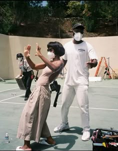 a man and woman standing on top of a tennis court holding hands in the air