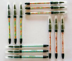 six pens are lined up on a white surface