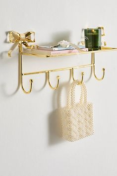 a wall mounted shelf with two hooks and a purse hanging from it's side