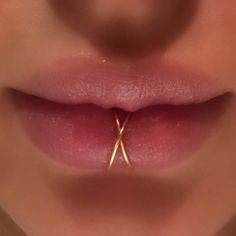 a woman's nose with two small gold scissors sticking out of the middle of her lip