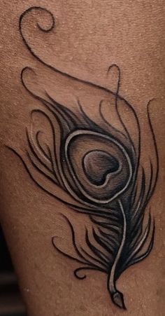 a black and white peacock feather tattoo on the back of a woman's leg