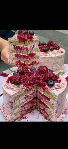 three layered cake with berries and blueberries on each layer, cut into four pieces