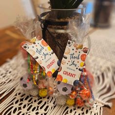 two small bags filled with candy sitting on top of a table next to a potted plant