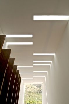 an empty room with white walls and ceiling lights on the ceiling is lit by recessed lighting