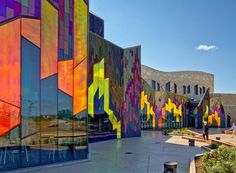 the colorful building has many different colored designs on it's walls and sides, along with people walking by