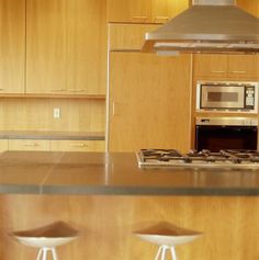 a kitchen with wooden cabinets and white stools