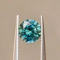 a blue and green diamond sitting on top of two toothbrushes