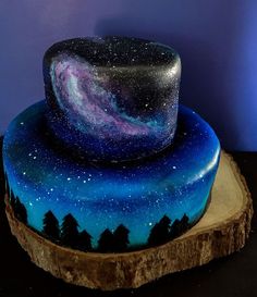 a cake that is on top of a tree stump with the night sky painted on it