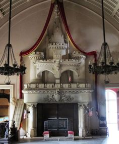 an ornate fireplace with chandeliers hanging from it's sides in a large room