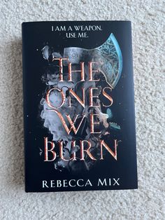 the book cover for the ones we burn by rebeca mix is laying on a white carpet