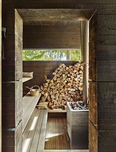 the inside of a cabin with wood stacked up