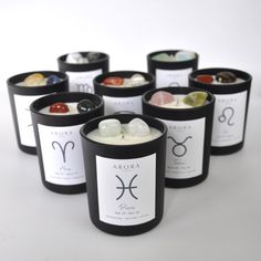 seven zodiac candles are arranged in rows on a white surface, each with their own astro sign