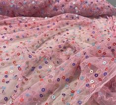 pink fabric with multicolored flowers and sequins on the top, laying flat