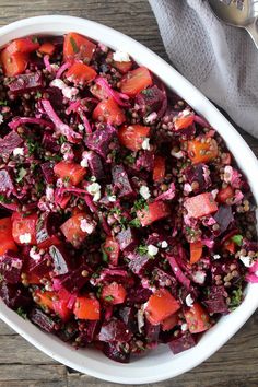 a white bowl filled with beets, onions and feta cheese on top of a wooden table