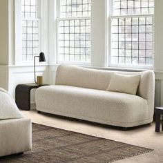 a living room with two couches and a rug in front of three windows on the wall