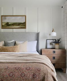 a bedroom with a bed, dresser and painting on the wall above it's headboard