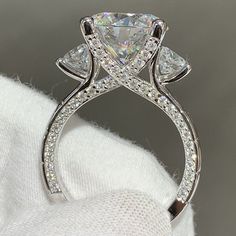 a close up view of a diamond ring on top of a white cloth with the background