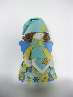 a small doll with a blue dress and yellow hat on it's head, sitting in front of a white background