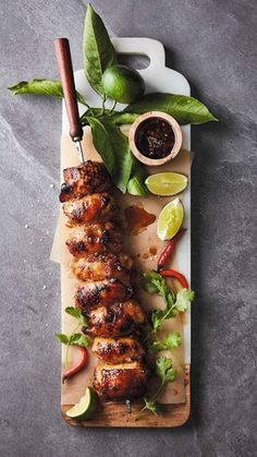 meat on a cutting board with limes and ketchup