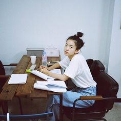 a woman sitting at a wooden table with papers on it