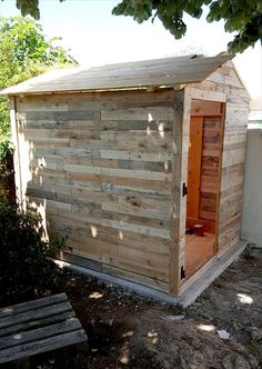 a small wooden outhouse sitting next to a tree