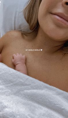 a close up of a person laying in bed with a baby on her chest and the words my whole world written across it