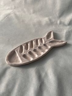 a metal leaf shaped dish on a white sheeted bed spread with the rest of it's body visible