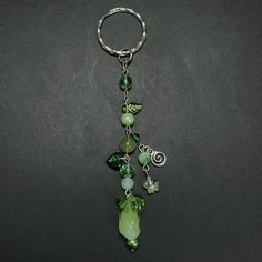 a keychain with green beads and charms hanging from it's side on a black surface