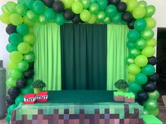 a minecraft themed birthday party with green and black balloons, tissue paper streamers, and a creeper bed