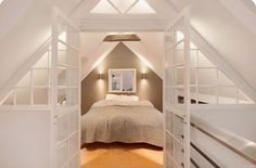 an attic bedroom with white walls and wooden floors