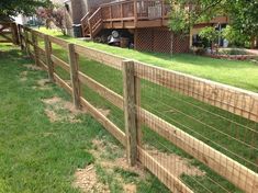 a wooden fence in front of a house with grass on the ground and stairs leading up to it