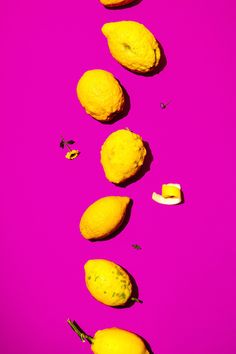 five lemons are arranged on a bright pink background