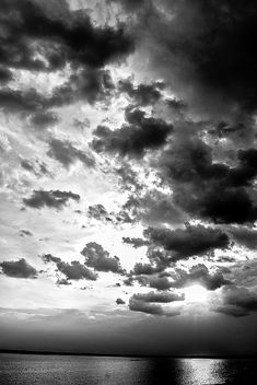 black and white photo of clouds over the ocean