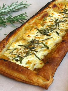 a long rectangular pastry with cheese and herbs on it next to two slices of bread