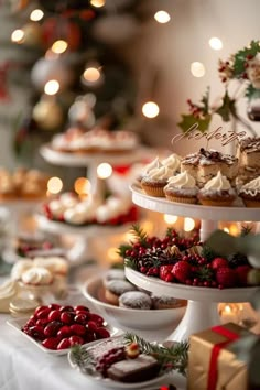 a table topped with lots of cakes and cupcakes covered in frosting next to christmas decorations