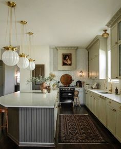 a kitchen with white cabinets and an island in the middle is lit by hanging lights