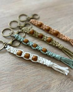 three key chains with beads and tassels on top of a wooden table next to each other